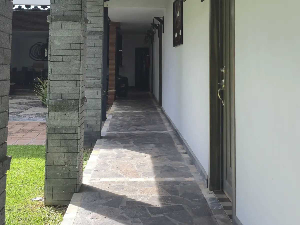 Pasillo techado con lámparas de herrería junto al jardín